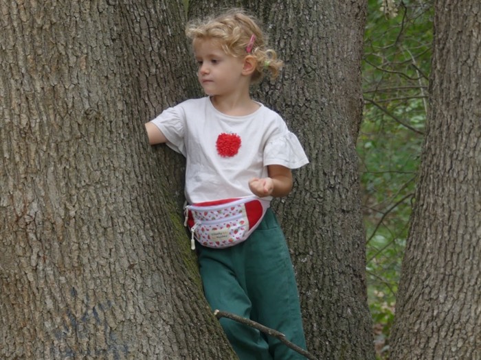 Enfant portant son sac banane Cheeky Monkey Fraise en forêt